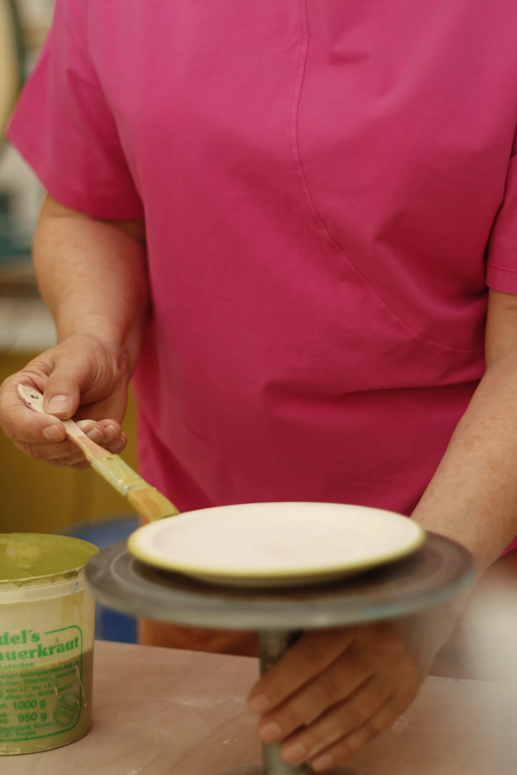 A plate is glazed with a brush on a banding wheel