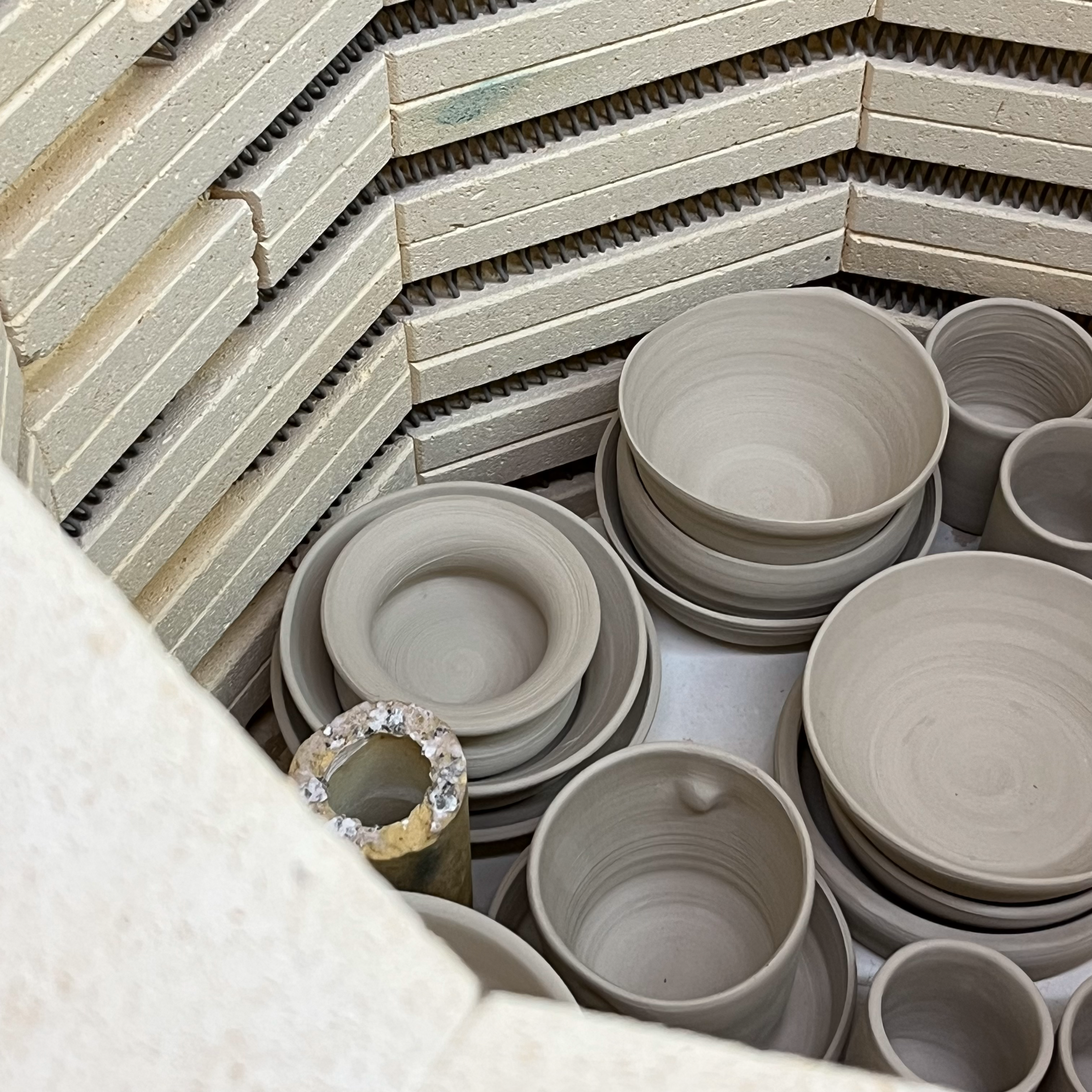 Unfired bowls and cups in the open kiln