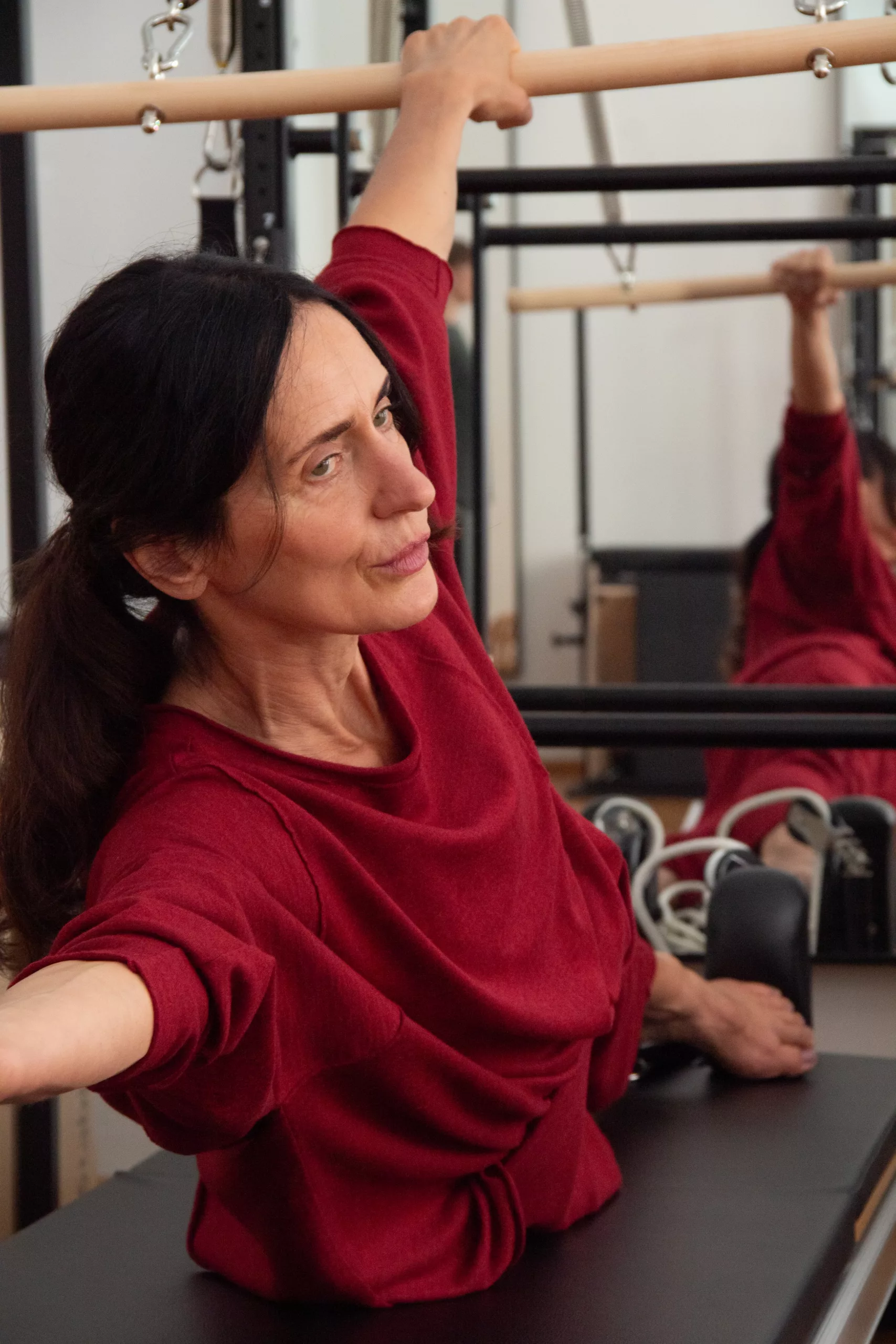 Iris dehnt sich an der Stange eines Pilates-Geräts