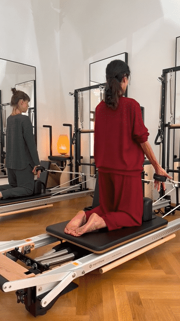Iris kniet auf dem Reformer und zieht an den Seilen
