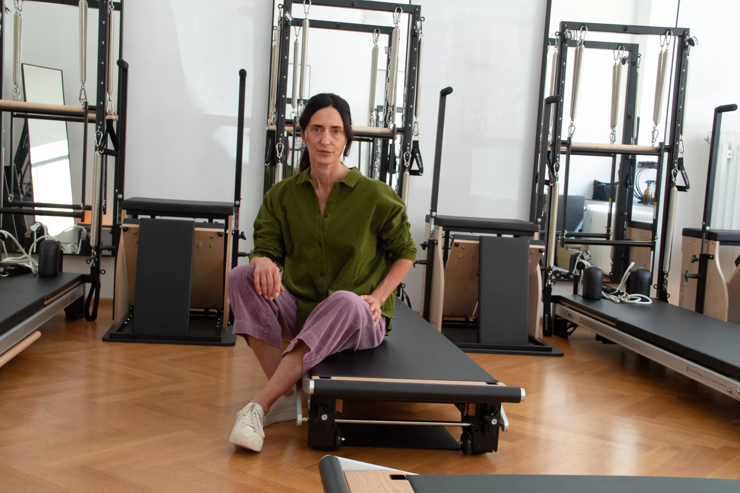 Iris sitzt in ihrem Pilates-Studio auf einem Reformer