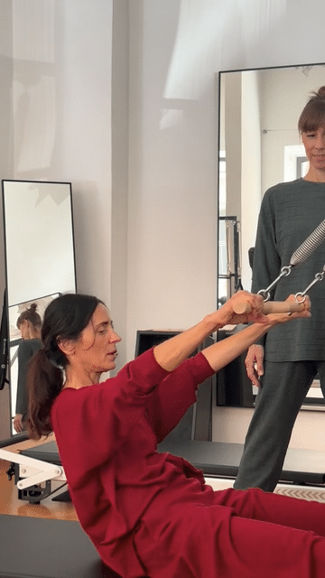 Iris macht eine Übung auf dem Reformer, Julia schaut zu