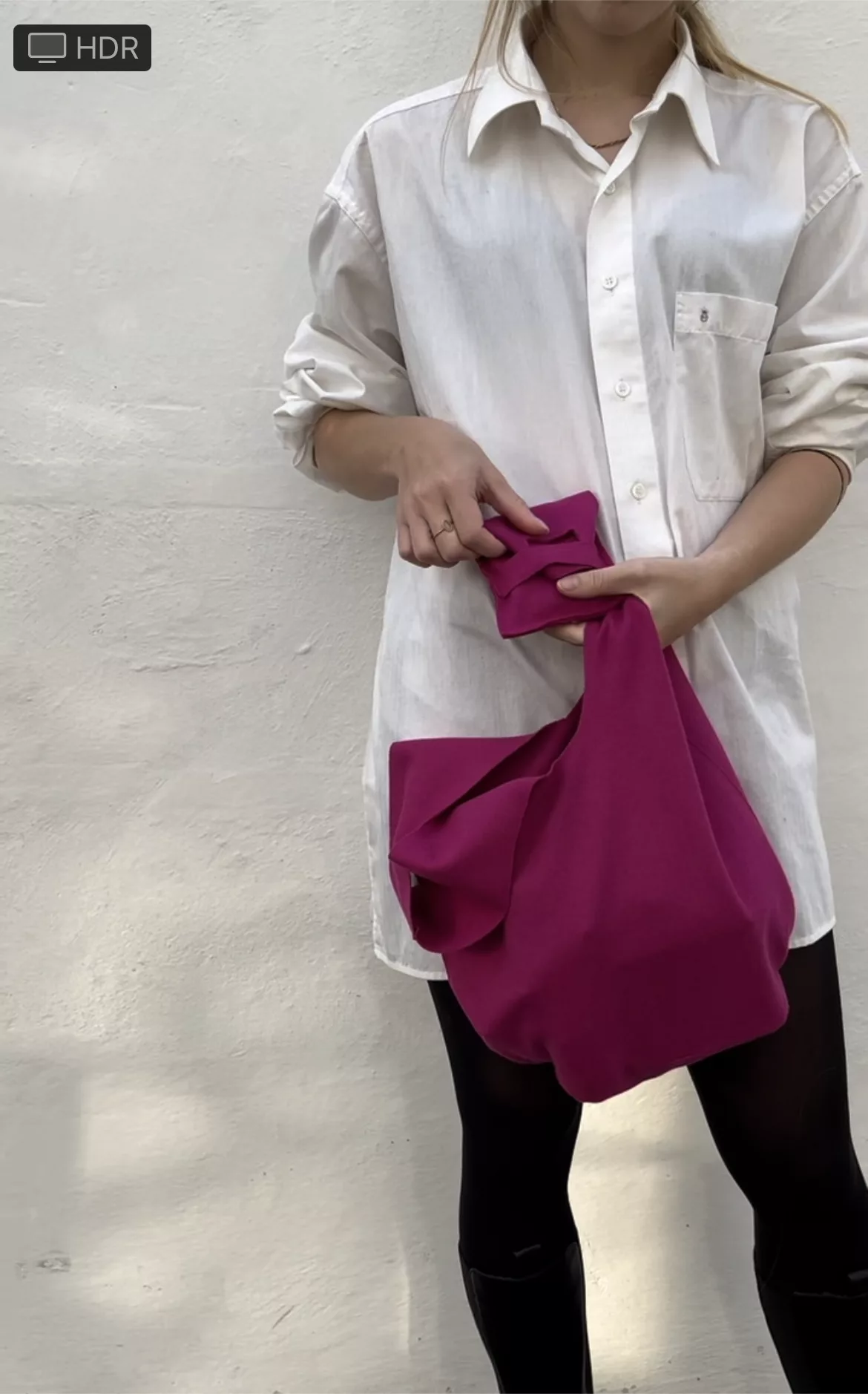 Person in a white shirt with a magenta knot bag and phone pouch