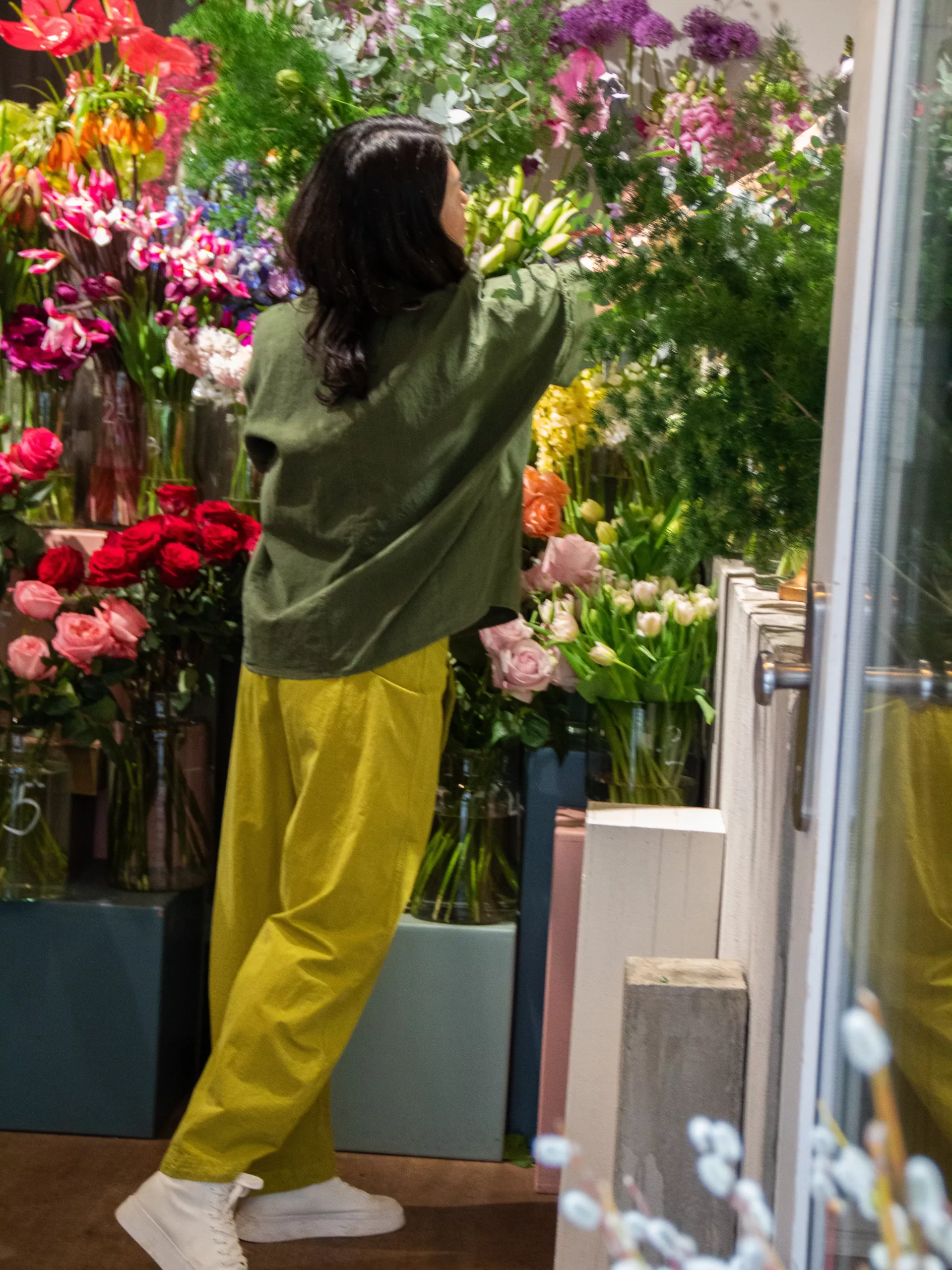 Ji greift von hinten gesehen in die Blumenauslage