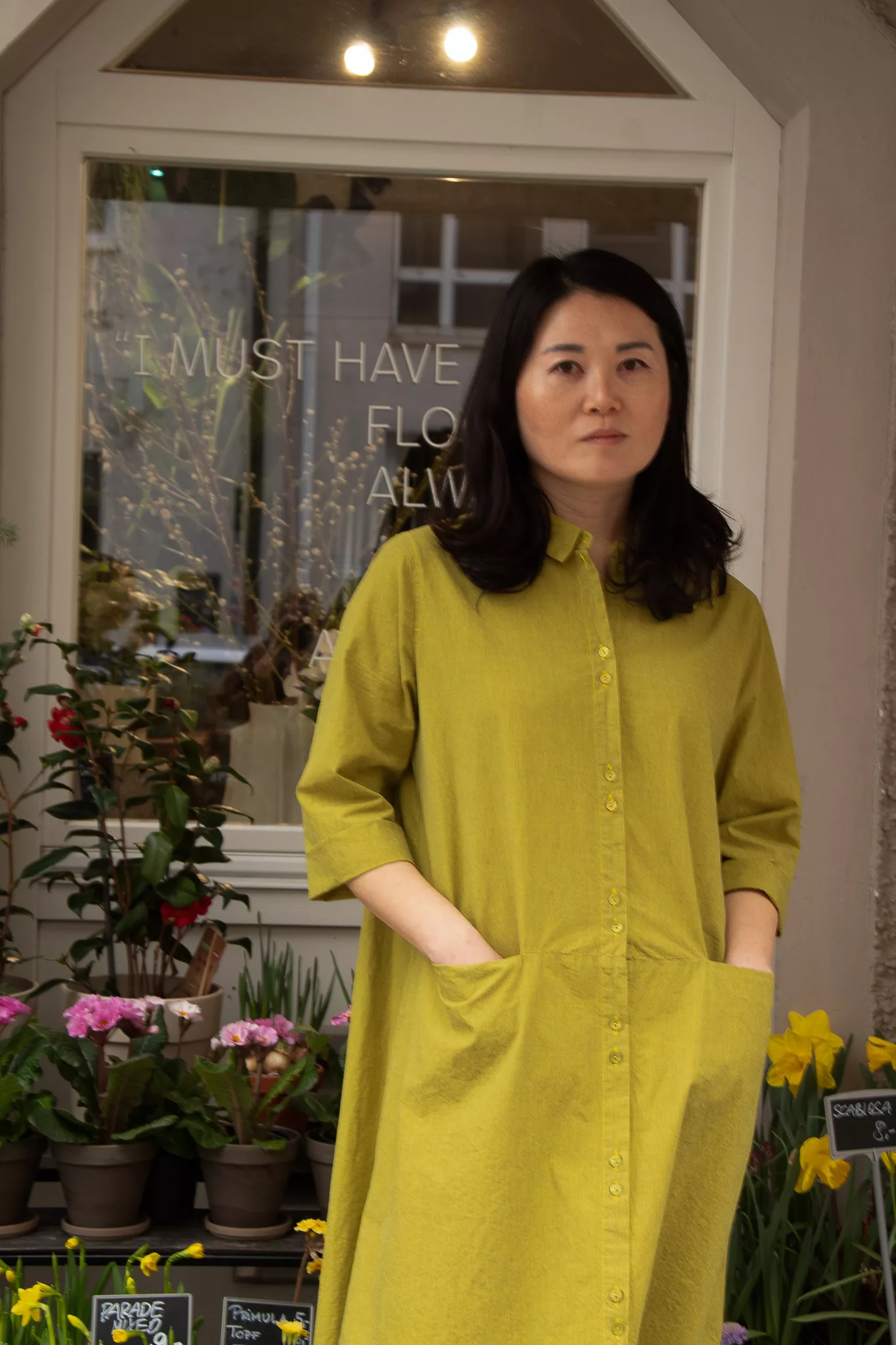 Ji in limettengrünem Kleid vor ihrem Laden