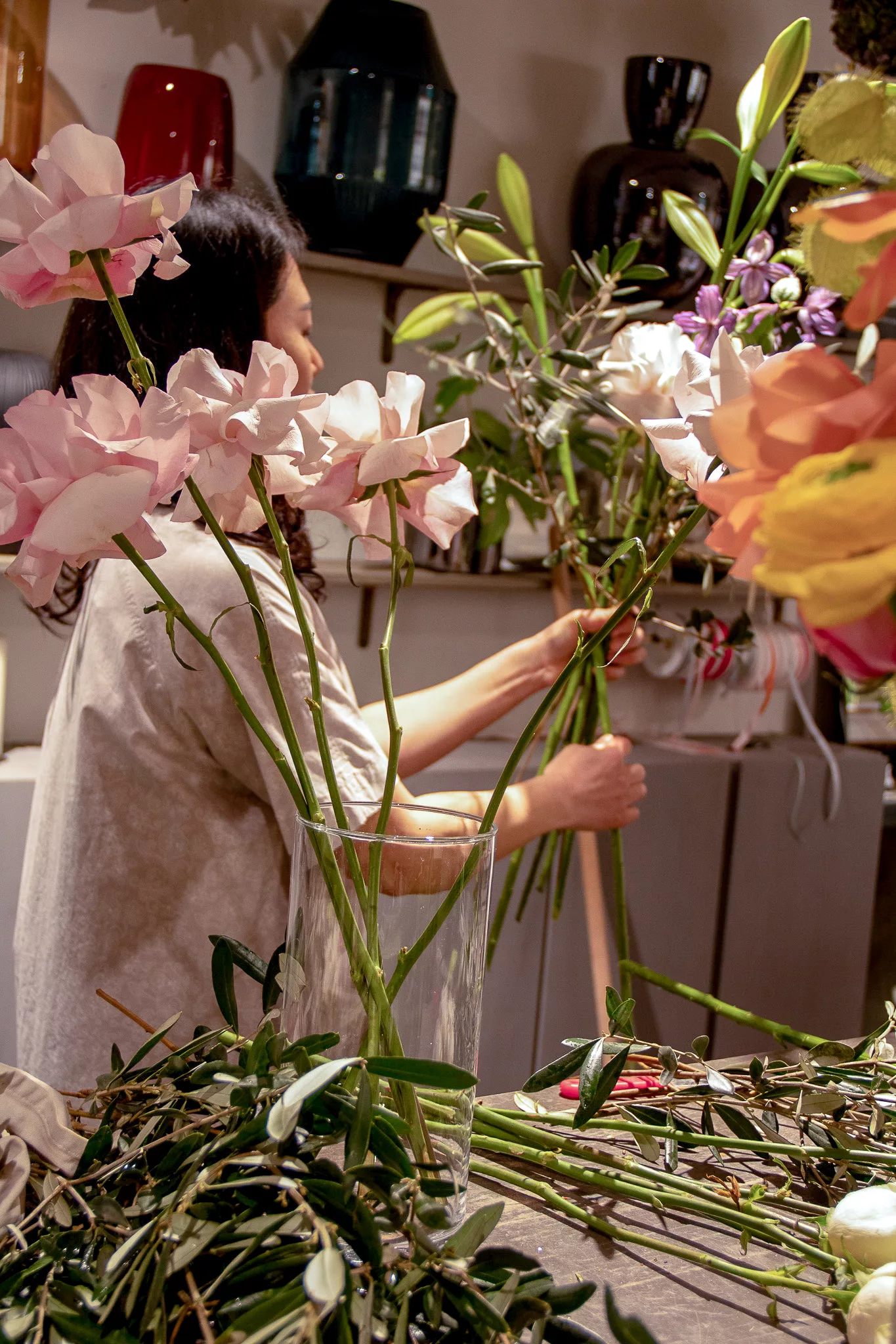 Ji arrangiert Blumen am Werktisch
