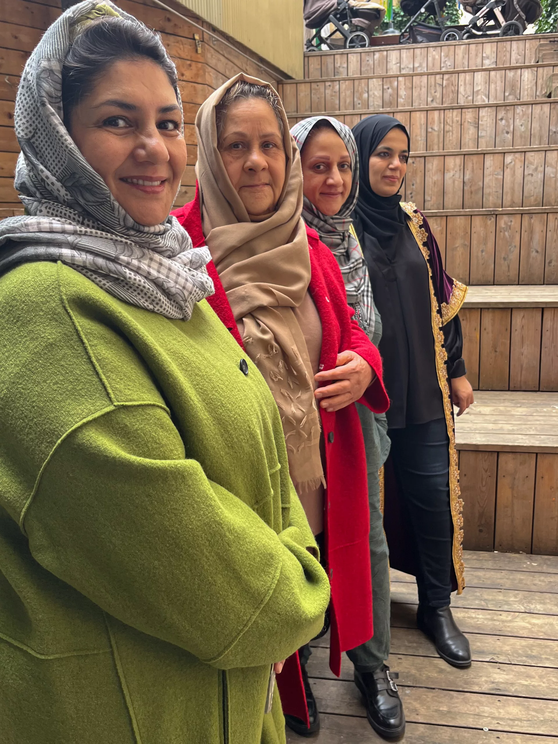 Four smiling women in coats and headscarves