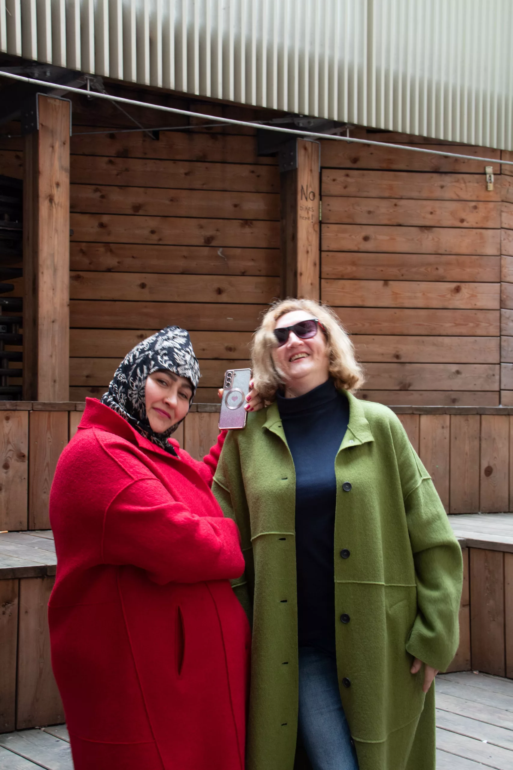 Two laughing women in a red and a green coat