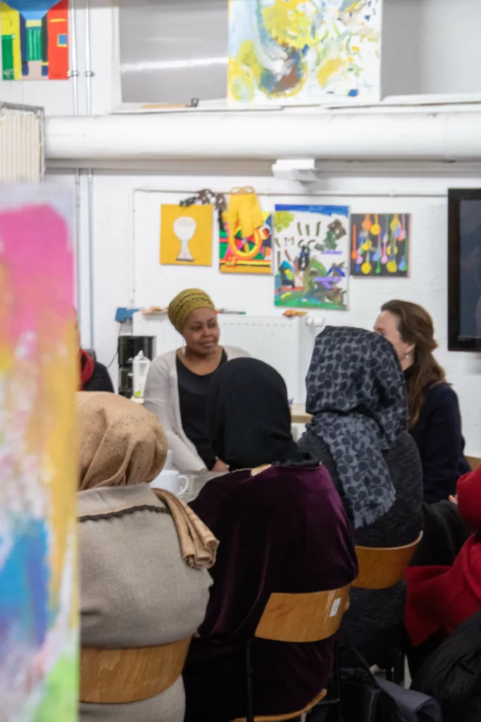 Women at tables in the women's café, paintings on the walls