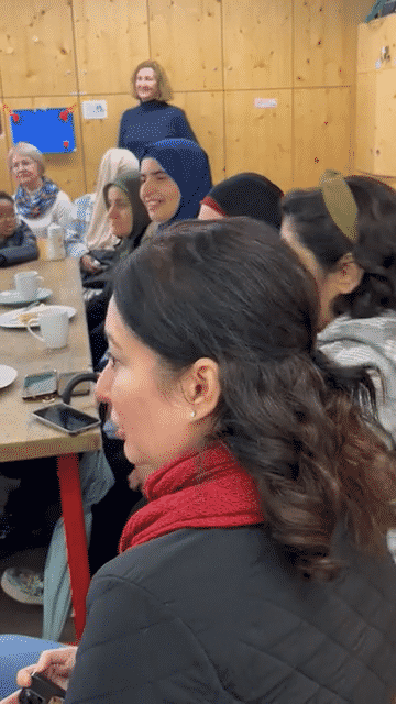 Women at the long table listening to a speaker