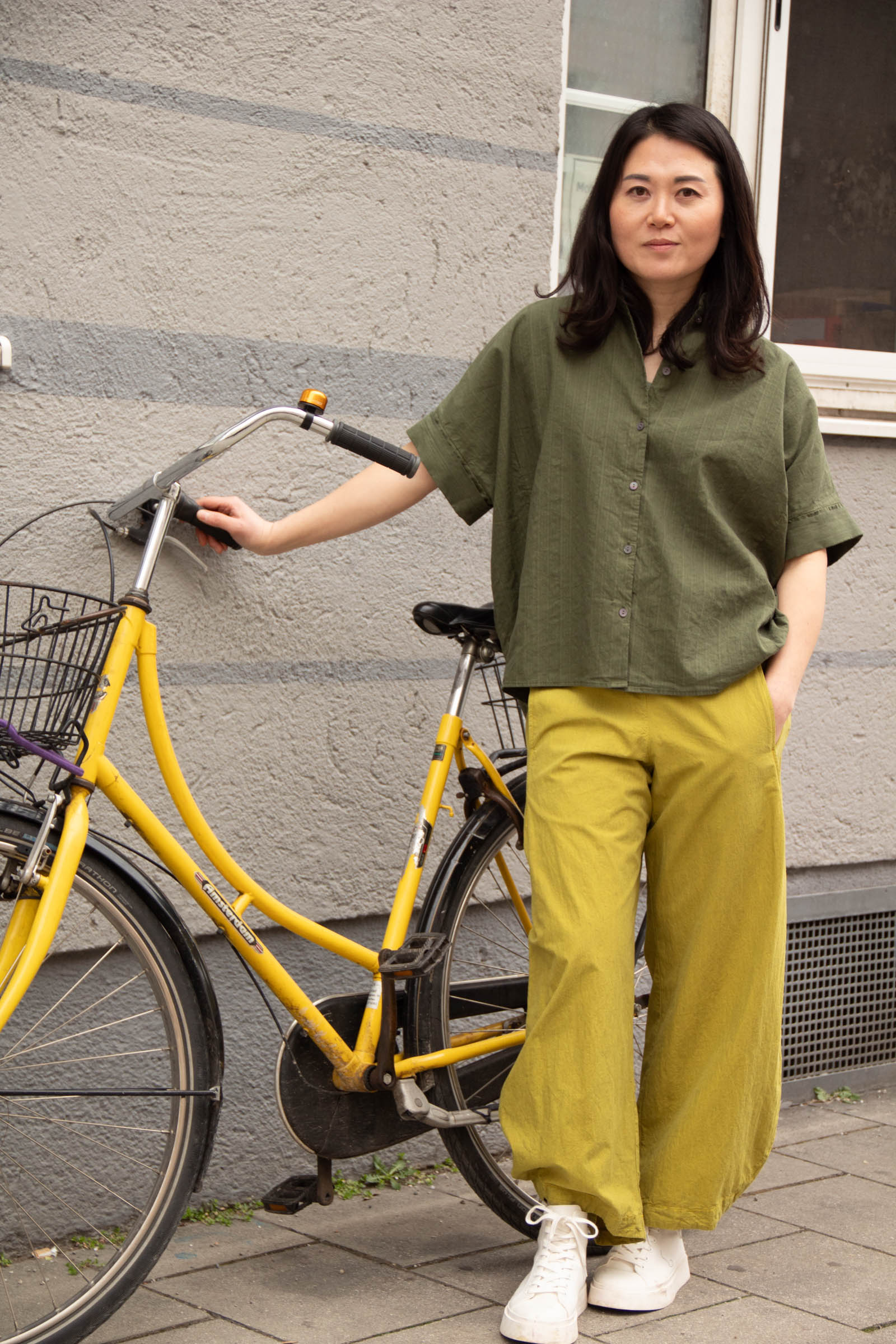 Ji lehnt neben ihrem gelben Fahrrad