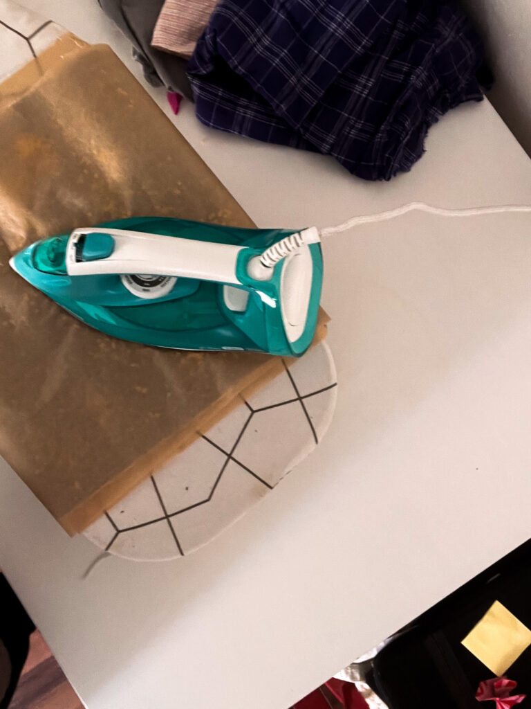 Bügeleisen auf Backpapier über dem Stoff