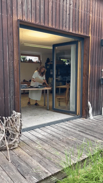 Blick vom Garten durch die offene Glastür ins Atelier