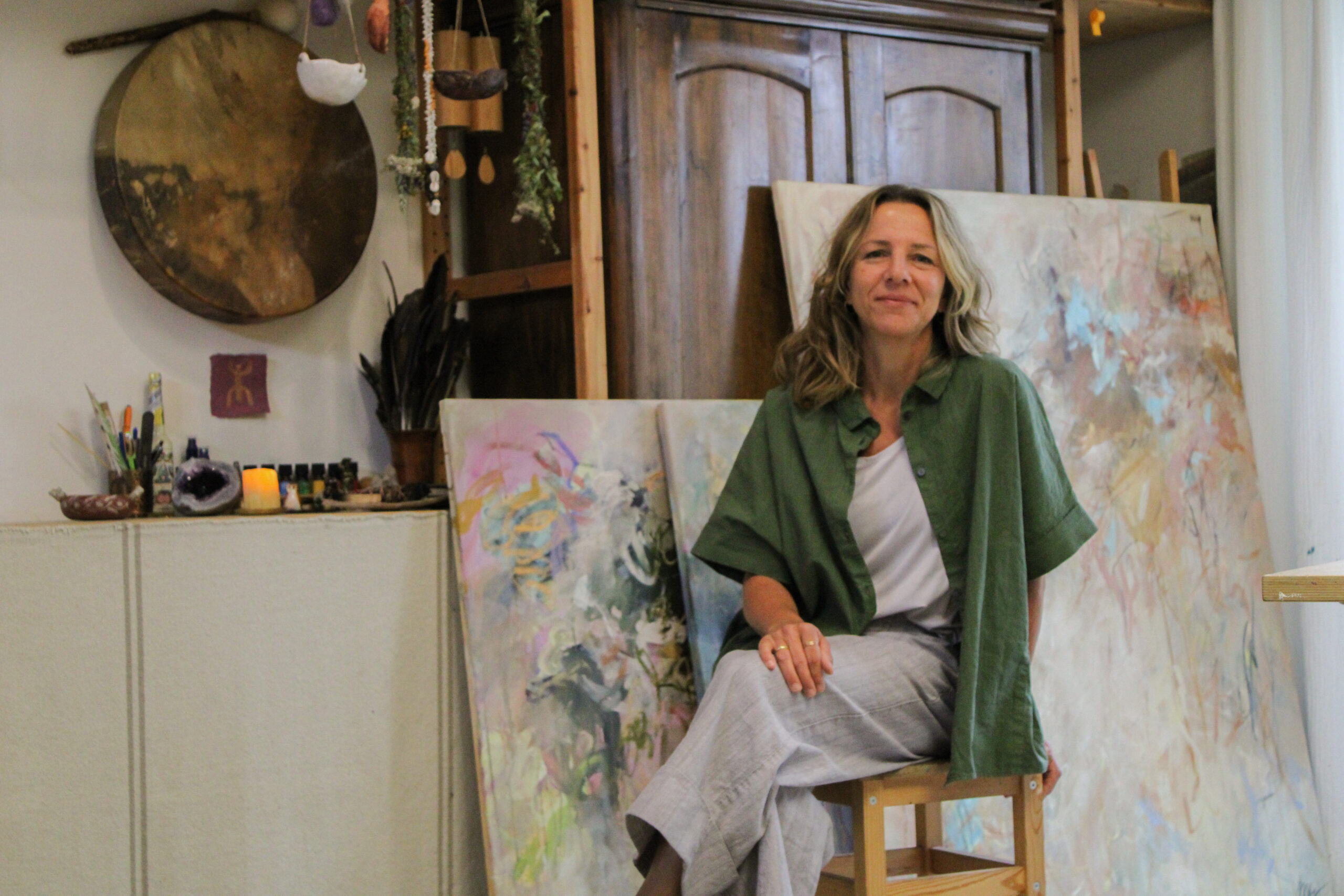 Marlene sitzt in ihrem Atelier zwischen Leinwänden