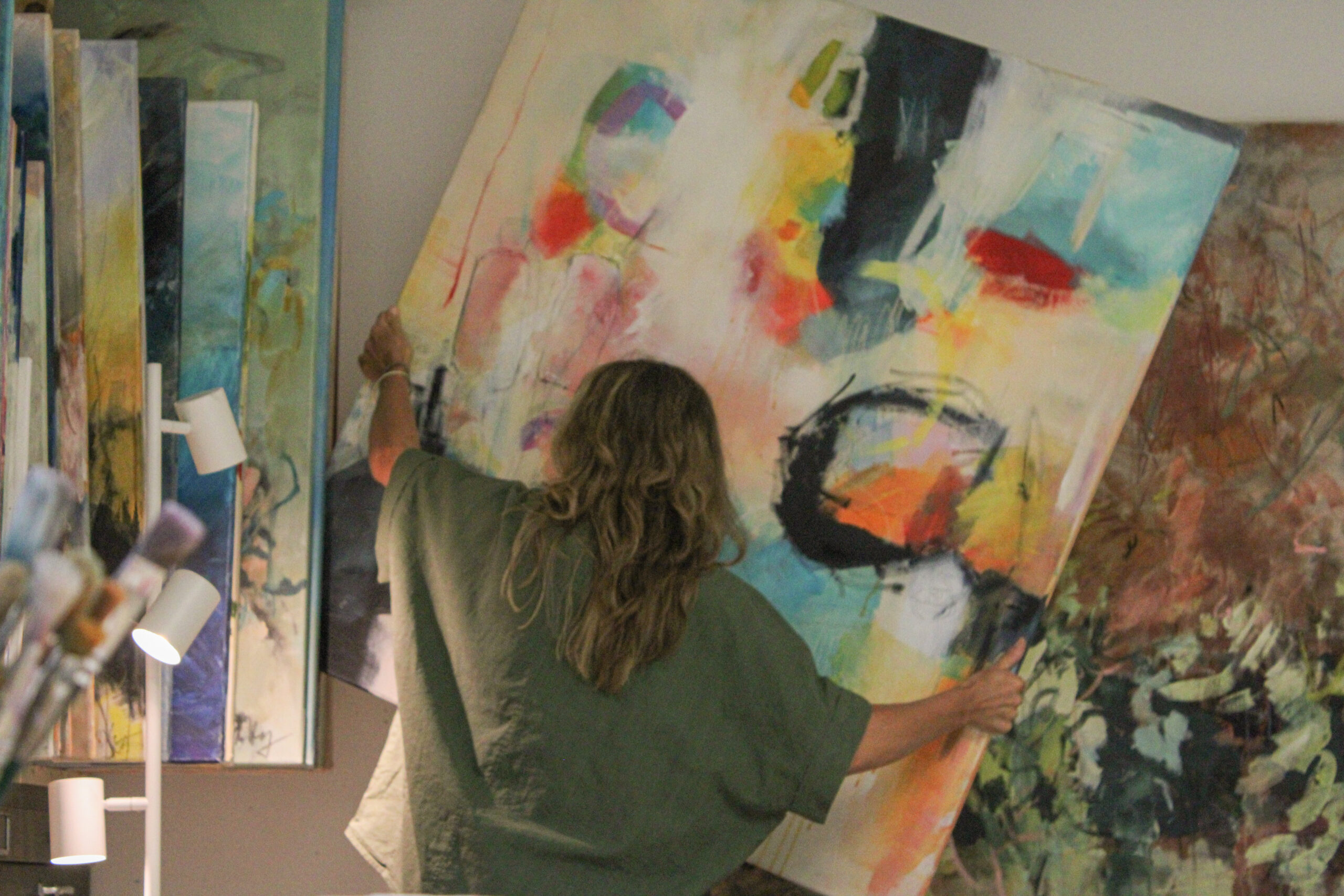 Marlene lehnt eine bunte Leinwand an die Wand