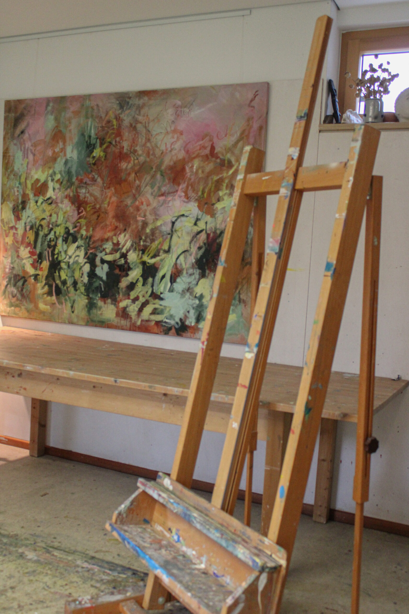 Staffelei vor einem großen Gemälde im Atelier