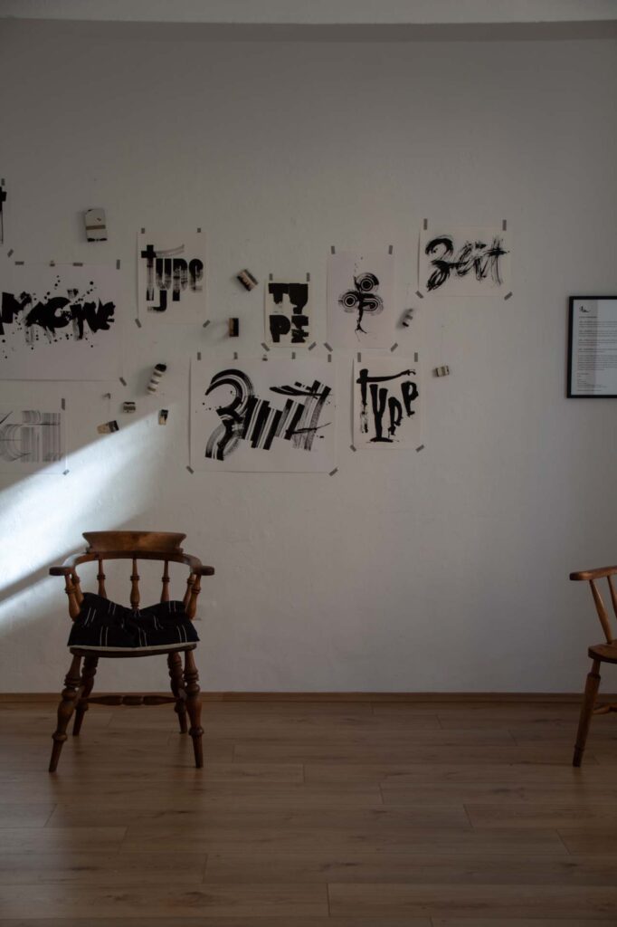 Raum mit Kalligrafien an der Wand und einem Holzstuhl