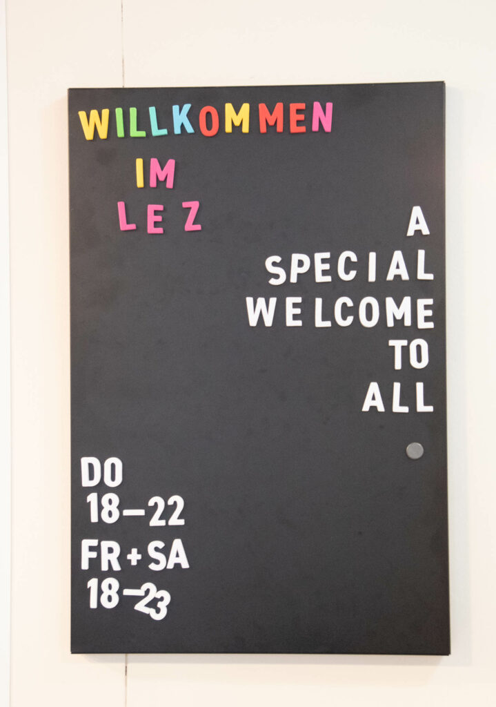 Schild: Willkommen im LeZ, a special welcome to all. Donnerstag 18 bis 22 Uhr, Freitag und Samstag 18 bis 23 Uhr