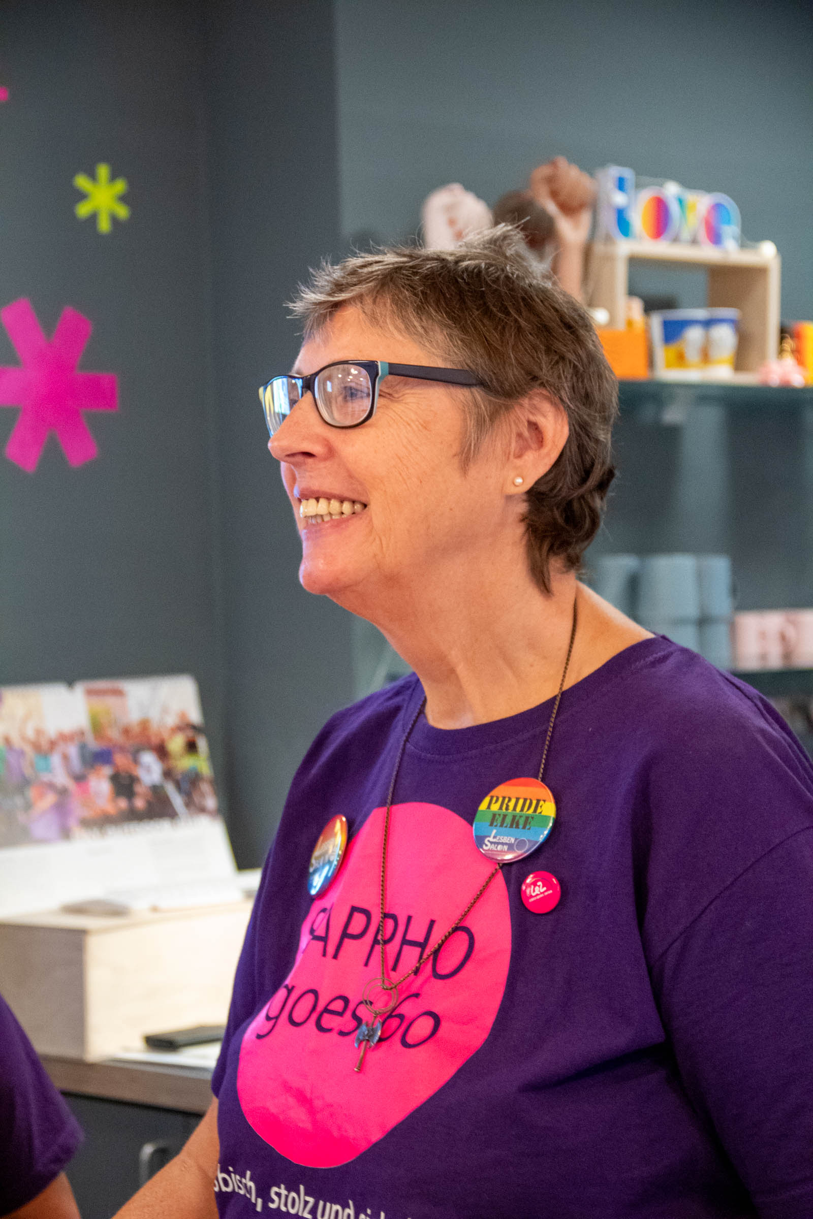 Frau mit Brille im Sappho-goes-60-T-Shirt lacht