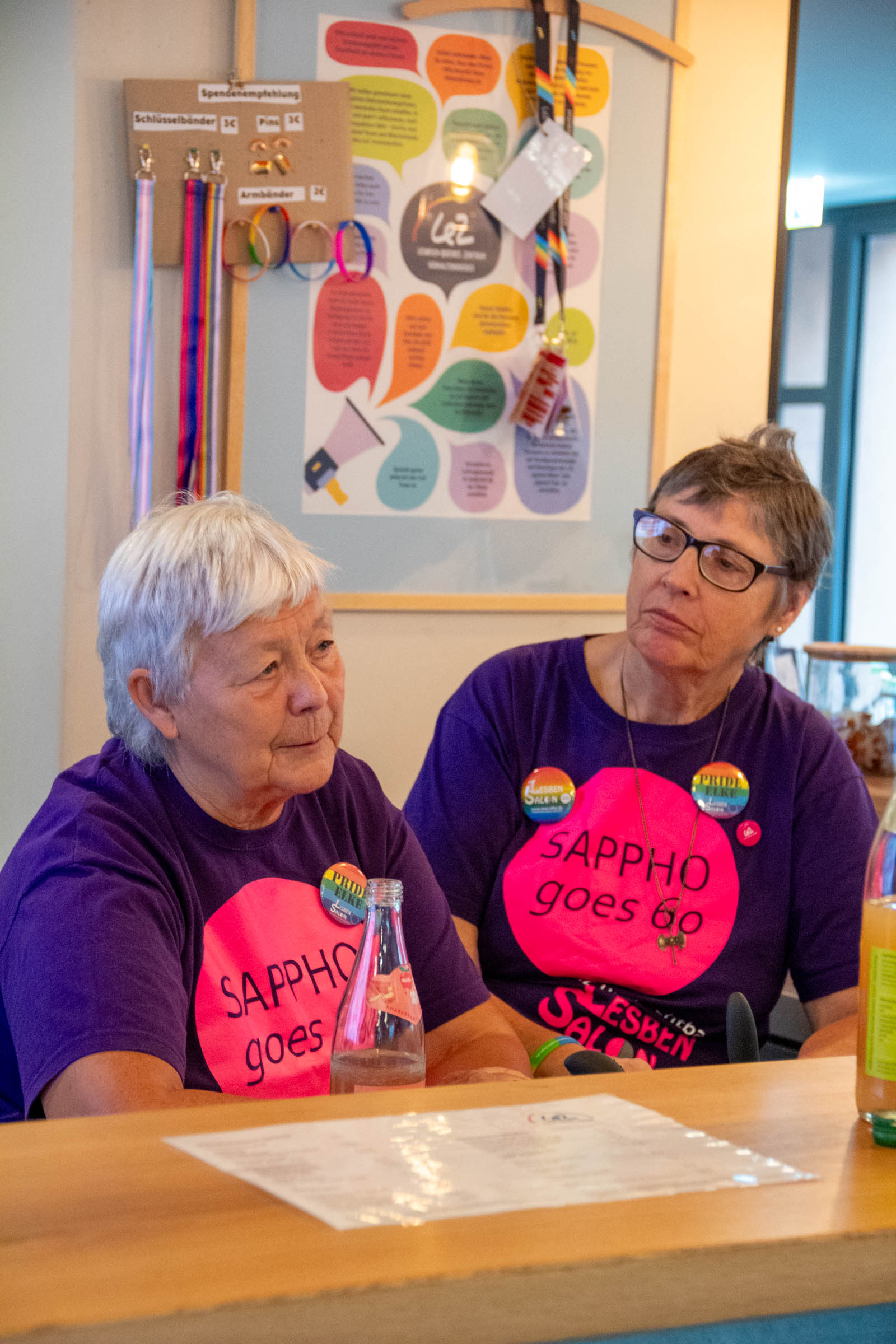 Zwei Frauen in Sappho-goes-60-T-Shirts am Tisch